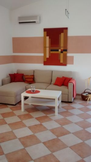 Apartment 1 Wohnzimmer mit Klimaanlage, Couch mit Ottomane, ausziehbar zu einem 2x2 Meter großem Bett. Spiele und Bücher sind vorhanden.