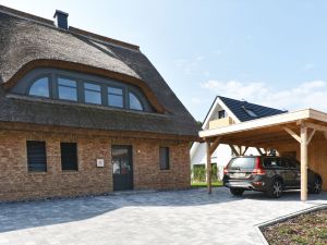 Rechte Seite der Reetadch-Villa Ostseefrisch mit Carport und Parkplatz