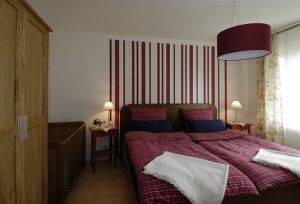 Das ebenerdig liegende Schlafzimmer besitzt ein Doppelbett 2*2 m, ein Kinderbett und eine Sitzgelegenheit mit Korbstühlen.