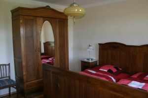 Schlafzimmer Erdgeschoss Im Schlafzimmer im Erdgeschoss befindet sich ein antikes Doppelbett, zwei Nachttischchen, ein großer Kleiderschrank, sowie eine Wäschekommode.