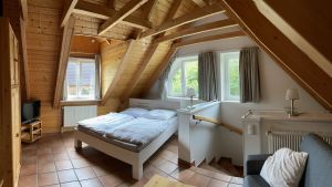 Das offene Schlafzimmer im Obergeschoss unseres Ferienhauses ist mit einem Doppelbett (Liegefläche 1,6 m) und mit einer Schlafcouch (Liegefläche 1,6 m) ausgestattet