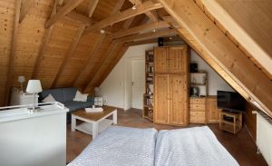 Im Dachgeschoss befindet sich ein Doppelbett sowie eine Schlafcouch mit Sitzgruppe. Hinten im Bild die Tür zum zweiten Schlafzimmer.