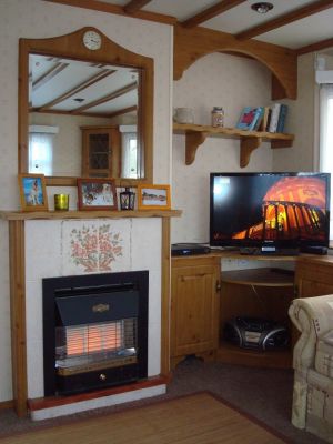 Wohnzimmer mit Kaminofen komfortabel eingerichtet mit großem Flatscreen-TV und funktionsfähigem Gas-Kaminofen für kühlere Herbstabende