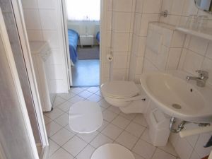 Badezimmer Das weiß geflieste Badezimmer mit geräumiger Duschkabine. Auch eine Waschmaschine für den kleinen Waschtag zwischendurch steht bereit. Eine Verbindungstür zum Schlafraum nach Osten öffnet den Blick auf die Ostsee.
