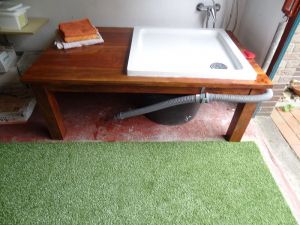 Im Bereich eines Abstellraumes (ehem. Garage) befindet sich die Warmwasser-Hundedusche. Ein Kunstrasen auf dem Boden verhindert, daß es evtl. nasse Füße für den Menschen gibt und er bietet sich zum Abtrocknen der geduschten Tiere an.