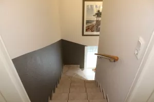Die Treppe ist gefliest, mit Handlauf.