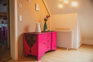 Schlafzimmer im OG Schlafzimmer 3 im Obergeschoß
Das Schlafzimmer ist mit einem 1,40 Meter Bett, Nachtschränckchen, Leselampen, einem Kleiderständer, Ventilator und einer kleinen Kommode ausgestattet.