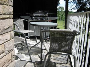 Balkon mit Tischen, Stühlen und modernem Gasgrill