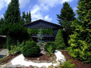 Ferienhaus EifelNest Zu sehen der schöne Steinvorgarten mit heimischen Tannen und Sträuchern, der das Ferienhaus EifelNest geborgen einrahmt.