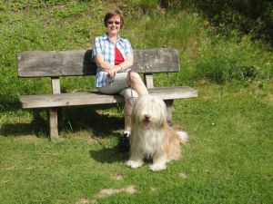 Frauchen und Kaja genießen die Sonne auf einer Bank im Ferienpark.
