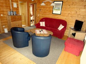 Wohnzimmer Haus 15 Vom Wohnzimmer aus gelangt man in sämtliche Räume des Hauses. Neben der Sitzgarnitur mit Couchtisch steht der Flachbildschirm des SAT-Anschlusses und im darunter befindlichen Schrank Videorekorder und DVD-Player.