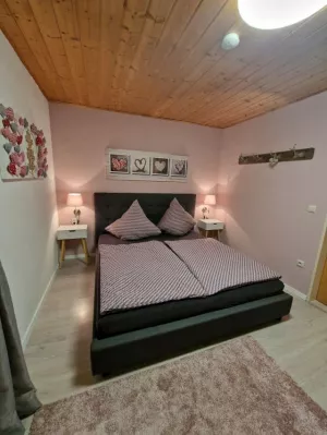 Schlafzimmer mit Doppelbett, zweitürigem Schrank, zwei Nachttischen und Garderobe. Zum Schlafzimmer gehört eine separate Toilette mit Waschbecken.