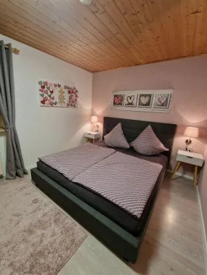 Schlafzimmer mit Doppelbett, zweitürigem Schrank, zwei Nachttischen und Garderobe. Zum Schlafzimmer gehört eine separate Toilette mit Waschbecken.