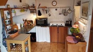 Küche Links: Beistelltisch mit Rollen, Anrichte (Marmorplatte). Mitte: Platte mit Mini-Backofen, 3-flammigen Gasherd, Wasserkocher. Rechts: Spüle, Küchenbüffet, rechts daneben (nicht sichtbar): Tür zumr Abstellkammer