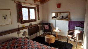 Schlafraum Sitzecke neben Doppelbett 2 Lederstühle, Klappschreibtisch unter Fenster, großer Fernseher abgedeckt neben Gardine. Hinter Gardine rechts: Hochbett, Hängekommode, Treppe nach unten