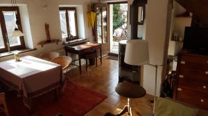 Wohnzimmer Richtung Eingangstür Von Küche aus gesehen. Rechts: Schlafsofa, Kommode mit Fernseher. Links: Esstisch, Antik-Schreibtisch
