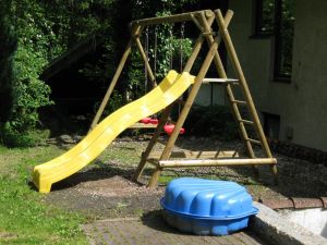 Der Spielplatz mit Schaukel, Rutsche und Sandkasten.