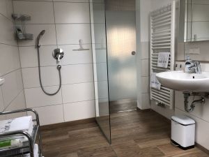 Eine ebenerdige Dusche und daneben das Waschbecken.