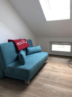 Der Raum zwischen dem Wohnbereich und dem Schlafzimmer ist hell und feundlich und ist mit einer Auszugscouch und einem Spielbereich ausgestattet.