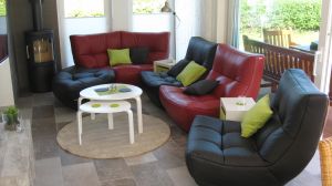 Der Wohnbereich mit hochwertiger und flexibler Couchgarnitur, Kaminofen, grossem TV, Fussbodenheizung, große bodentiefe Schiebetüren öffnen den Ausgang zur Süd-Terrasse und dem eingezäunten Garten mit Holzterrasse, Grill, Gartenmöbeln und Sonnenschirm. Im Garten befindet sich dann noch eine zusätzliche Hoch-Terrasse mit einem Strandkorb.