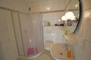 hat eine Dusche, Waschbecken, WC und einen Handtuchwärmer. Es gibt einen Fön und einen Kosmetikspiegel.