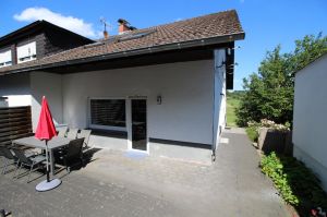 mit großem Tisch, Stühlen, Sonnenschirm und Grill.