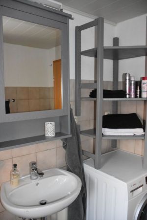 Badzimmer mit Dusche und großes Regal sowie Waschmaschine.