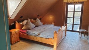 Schlafzimmer 1 DG mit Doppelbett und Zugang zur Dachterrasse mit Strandkorb.