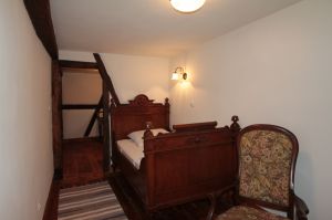 IN diesem kleinen gemütlichen Zimmer findet sich ein Bett, Kleiderschrank, 2 Sessel und ein anktikes Waschschränkchen