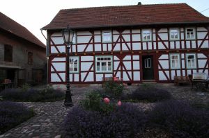 In den Beeten des kopfsteingepflasterten Hofes blühen Rosen und Lavendel