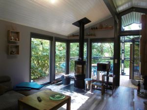 Wohnzimmer mit freistehenden Kaminofen und bodentiefe Fenster mit Blick in den Garten