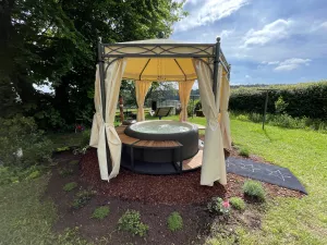 Whirlpool im Garten, umrahmt von Blumenbeeten und Liegewiese mit Blick auf die mannigfaltige Eifellandschaft