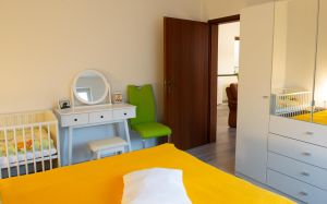 Blick aus dem Schlafzimmer ins Wohnzimmer, großer Kleiderschrank und optionales Babybett
