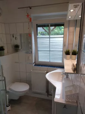 Das geflieste Bad besteht aus einem WC, Dusche und einem Handwaschbecken mit großem Spiegel.