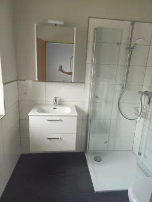 Elegantes Badezimmer mit ebenerdiger Dusche, Spiegelschrank und Fußbodenheizung.