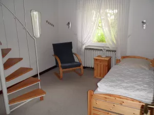 Das Dreibettzimmer hat unten ein Bett. Eine Wendeltreppe führt nach oben. Dort stehen 2 weitere Betten. Von dort gelangt man in einen Raum mit Dusche, WC und Handwaschbecken.